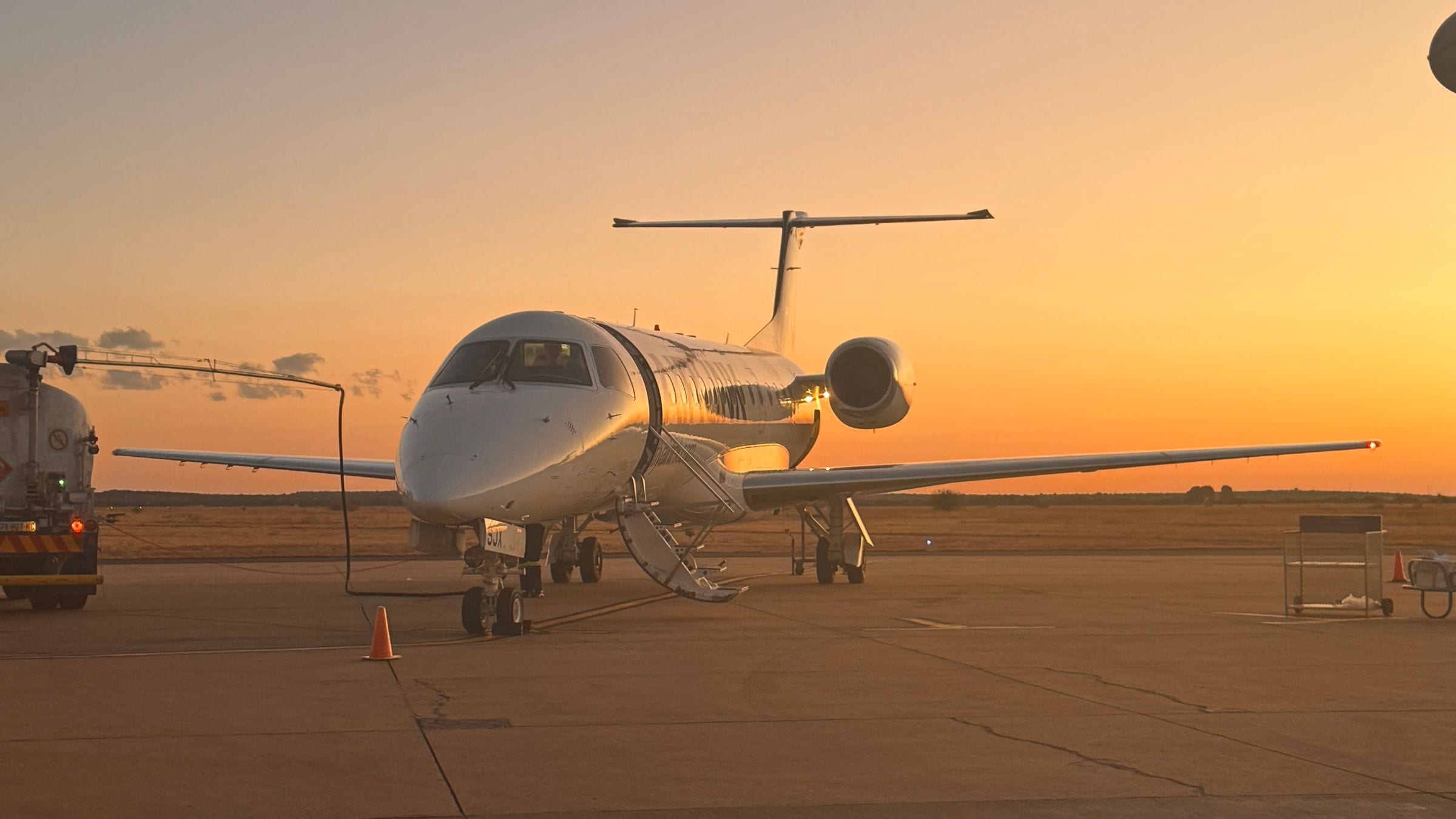 A private jet on the apron at dusk, fuselage catching the last light